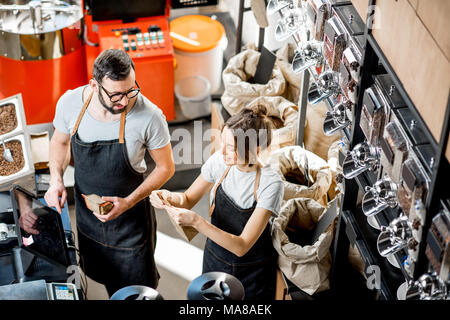 Deux vendeurs en uniforme et d'un poids de remplissage de sacs de café dans le magasin de café. Vue de dessus Banque D'Images