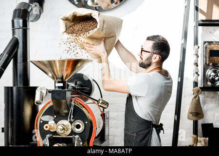 Man pouring Coffee beans dans la rôtissoire à l'intérieur de la machine Banque D'Images