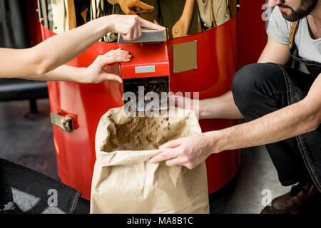 Verser les grains de café torréfiés dans le sac en papier de la machine torréfacteur pour vendre Banque D'Images