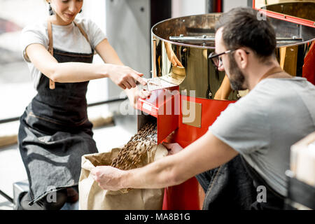 Verser quelques grains de café torréfiés dans le sac en papier de la machine torréfacteur pour vendre Banque D'Images