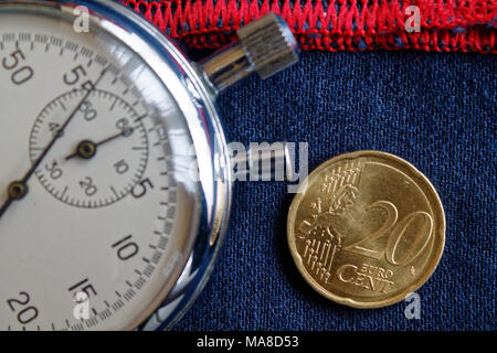 Pièce en euros d'une valeur nominale de 20 centimes d'euro et chronomètre denim bleu usé avec une bande rouge - toile de fond d'affaires Banque D'Images