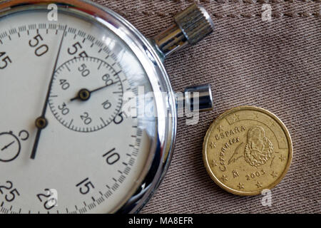 Pièce en euros d'une valeur nominale de 10 centimes d'euro (côté arrière) et un chronomètre sur toile Denim beige - business background Banque D'Images