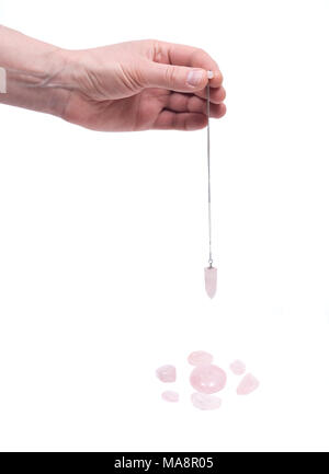 Young woman's hand holding a dégringolé sur pendule quartz rose quartz rose pierres isolé sur fond blanc Banque D'Images