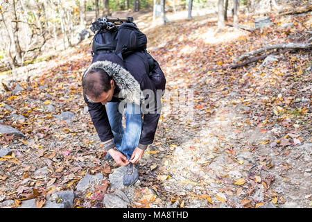 Jeune homme sur sentier de randonnée pédestre à travers le feuillage orange automne forêt d'automne lier chaussures sport avec de nombreuses feuilles sur chemin dans Harper's Ferry, West Virginia Banque D'Images