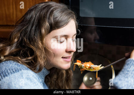 Portrait de gros plan visage jeune femme essayant d'hiver chaud chaud maison soupe de légumes de spoon, bouche ouverte smiling in cold sweater Banque D'Images