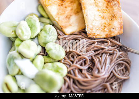 Gros plan macro de nouilles de sarrasin soba nourriture Japonaise, Fried tofu croustillant doré au four, des fèves vertes sur le chaud, le froid l'été, bol blanc Banque D'Images