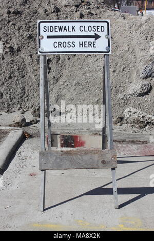 'Sidewalk cross fermé ici' construction permanent signe devant un tas de gravier utilisé pour détourner la circulation piétonne. Banque D'Images