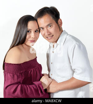 Jolie jeune femme enceinte portant une robe sans manches bordeaux debout avec ses mains devant elle tenant les mains de son mari avec pour Banque D'Images