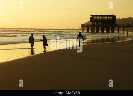 Durban, le KwaZulu-Natal, Afrique du Sud, surfeur en passant devant deux femmes hauts bas de pagayer dans surf uShaka plage, Golden Mile beachfront Banque D'Images
