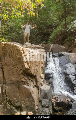 Jeune adulte garçon debout sur une petite cascade rencontrés sur le trek à Mainapi Netravali en cascade Wildlife Sanctuary, Goa. Banque D'Images