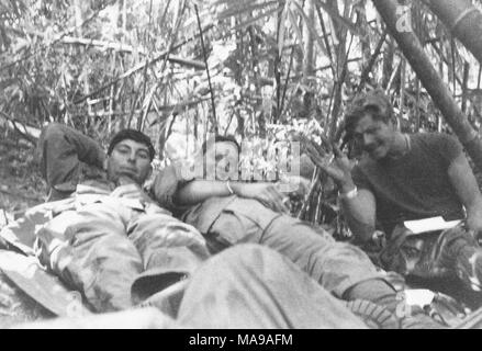 Photographie noir et blanc, montrant trois soldats, couché et assis sur le sol dans une forêt de bambou, un sourire et de forme vers la caméra, photographié au Vietnam pendant la guerre du Vietnam (1955-1975), 1971. () Banque D'Images