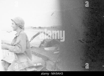 Photographie noir et blanc, partiellement obscurci, montrant un soldat, dans les trois-quart profil, portant un casque et fatigues, en passant devant le capot d'un véhicule militaire, photographié au Vietnam pendant la guerre du Vietnam (1955-1975), 1971. () Banque D'Images