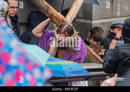 Londres, Royaume-Uni. 30 mars, 2018. Jésus est envoyé pour la Crucifixion et a à porter sa croix dans la foule - le plein air joueurs Wintershall, reconstitution de "La Passion de Jésus" le vendredi saint dans la pluie à Trafalgar Square. Il a comporté une distribution de plus de 100 bénévoles de dans et autour de Londres. Crédit : Guy Bell/Alamy Live News Crédit : Guy Bell/Alamy Live News Banque D'Images