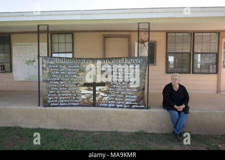 Cinq mois après la fusillade qui a coûté la vie à 26 First Baptist Church de Sutherland Springs, une femme assise à côté d'une bannière avec le nom de chaque victime pendaison à l'église rurale. Banque D'Images