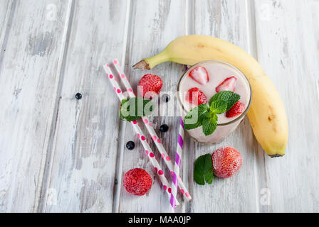 Rose d'été rafraîchissant smoothie ou milk-shake à la menthe, yaourt et fraises. dans le verre avec des ingrédients, sur table en bois blanc, copy space, top vi Banque D'Images