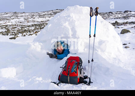 Sourire satisfait dans une maison de tourisme de neige igloo avec un vin métal-verre d'alcool des boissons sur l'arrière-plan d'un paysage de montagne d'hiver Banque D'Images