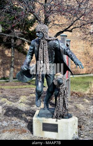 Aurora, Illinois, USA. Une statue dédiée aux pompiers Aurora orné d'un chapeau et un foulard pendant l'hiver de l''Aurora Regional Fire Museum. Banque D'Images