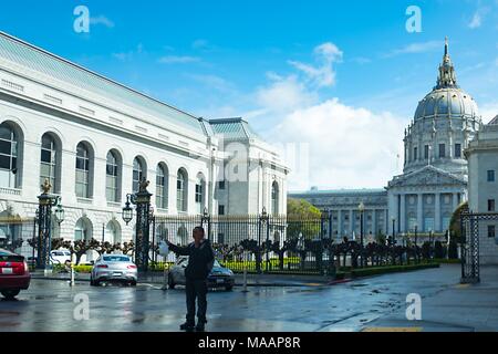 Un homme se tient au premier plan en face de la coupole ornée de San Francisco City Hall dans le centre municipal de San Francisco, Californie, le 14 mars 2018. () Banque D'Images