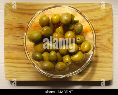 Des plats typiquement méditerranéens, les olives marinées vert sur une planche à découper. Banque D'Images