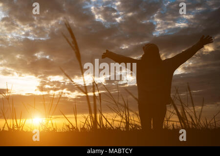 Silhouette de femme debout sur le terrain pendant le coucher du soleil. Banque D'Images