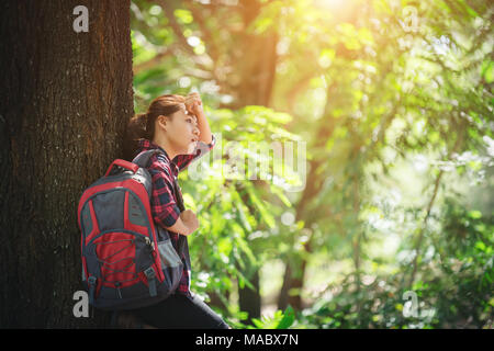 Randonneur fatigué femme se détend avec un grand sac à dos, au cours de promenade dans la forêt. Banque D'Images