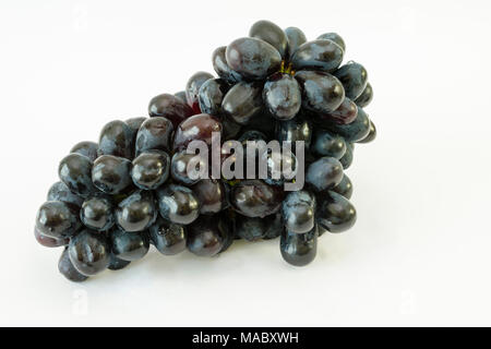 Tas de raisins sans pépins noirs (Vitis vinifera) avec des gouttes d'eau sur un fond blanc Banque D'Images