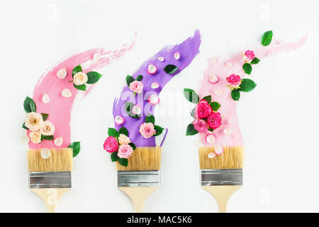 Pinceaux avec taces de tons rose et violet, roses et pétales, sur un fond blanc avec l'exemplaire de l'espace. Printemps peinture télévision créative lay. Accueil de Banque D'Images