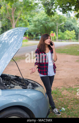 Jeune femme avec voiture tombe en panne et elle appelle les services d'urgence. Banque D'Images