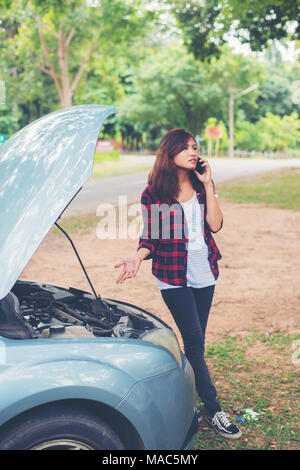 Jeune femme avec voiture tombe en panne et elle appelle les services d'urgence. Banque D'Images