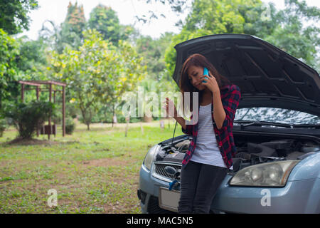 Jeune femme avec voiture tombe en panne et elle appelle les services d'urgence. Banque D'Images