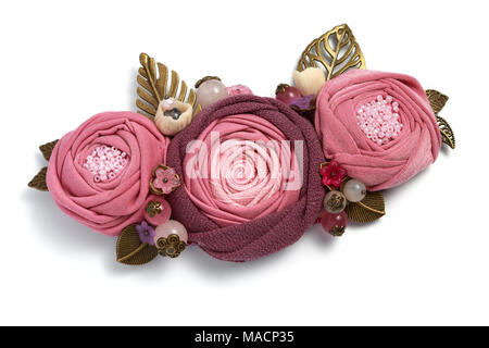 Broche à la main sous la forme de trois fleurs en tissu rose sur fond blanc Banque D'Images