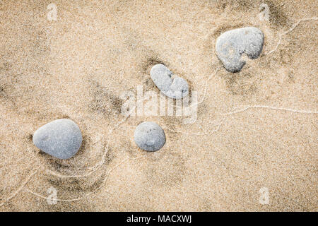 Un arrangement de pierres grises de la création d'un modèle de modération aléatoire sur une plage de sable. Banque D'Images