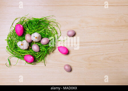Décorations de Pâques sur fond de bois avec de l'herbe, du poulet et des œufs. Vue d'en haut. Banque D'Images