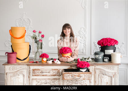 Jeune femme plantes fleuriste organiser dans le magasin de fleurs. Les gens, les entreprises, de la vente et de l'art floral concept. Bouquet de roses rouges Banque D'Images