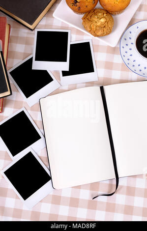 Livre écrit en blanc avec des impressions de photo sur un chèque, nappe avec du café et des gâteaux (chemins). Banque D'Images