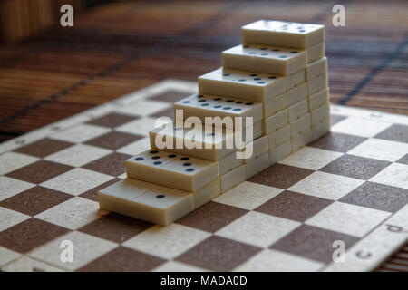 Pyramide de pièces domino sur la table en bois bambou brown background Banque D'Images