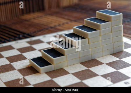 Pyramide de pièces domino sur la table en bois bambou brown background Banque D'Images