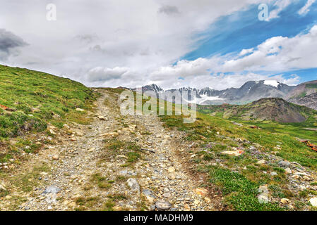 Rocky route raide dans le haut des montagnes, herbe verte et des glaciers sur le fond bleu du ciel et nuages Banque D'Images