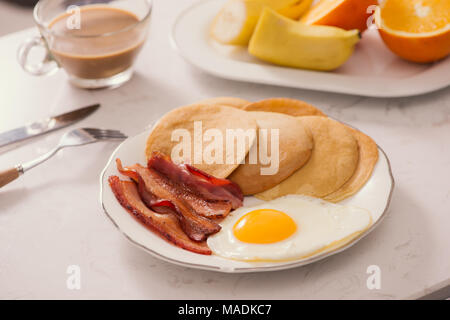 Assiette petit-déjeuner avec des crêpes, des œufs, du bacon et des fruits. Banque D'Images