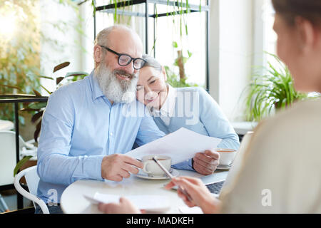 L'homme et la femme mature points de lecture et des conditions du contrat ou de l'accord au cours de réunion avec agent dans cafe Banque D'Images