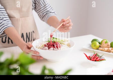 Femme chef préparer la soupe traditionnelle vietnamienne Pho bo avec des herbes, de la viande, des nouilles de riz Banque D'Images