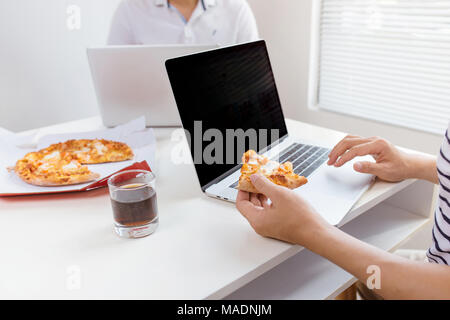 Le déjeuner et le peuple concept. Happy business team eating pizza in office Banque D'Images