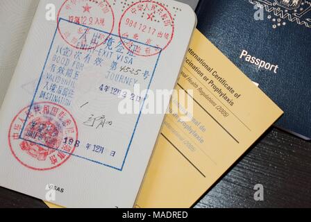Passeport bleu et ouvert passeport avec visa d'Asie timbres et un certificat international de vaccination Banque D'Images