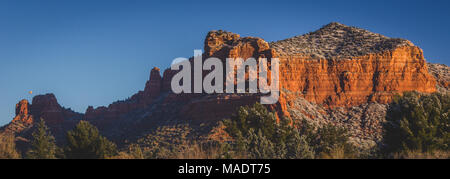 Des formations de roche rouge couverte de plaques de neige au lever du soleil avec un ciel clair et un ballon à air chaud dans la distance, Coconino National Forest, Arizona Banque D'Images