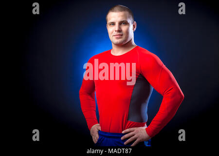 Un solide brun velo dans un sport rouge rush guard posing against a blue un éclairage sur une base isolée noir Banque D'Images