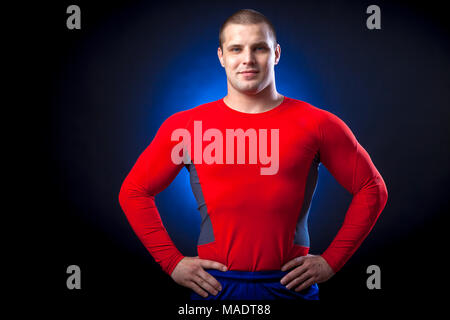 Un solide brun velo dans un sport rouge rush guard posing against a blue un éclairage sur une base isolée noir Banque D'Images