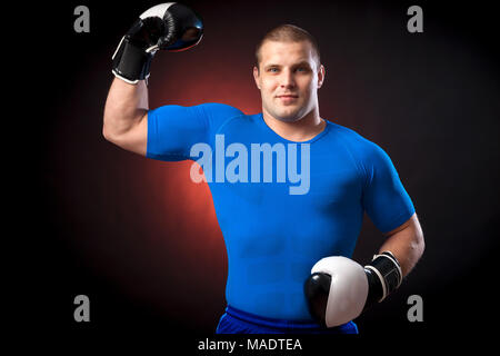 Un solide brun Anti-rouille boxer dans un sport bleu rush guard et en noir et blanc des gants de boxe show biceps contre un feu rouge sur une bla Banque D'Images