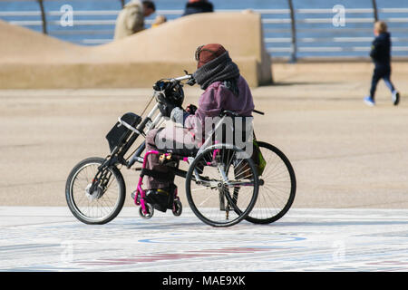 Utilisateur de fauteuil roulant à Blackpool, Lancashire. Météo britannique. 1er avril 2018. Calme, froide journée ensoleillée sur la côte les vacanciers arrivent à la côte dans l'espoir d'un printemps chaud. Les conditions devraient s'aggraver en début d'après-midi avec la pluie et la grêle averses prévues. Credit : MediaWorldImages/Alamy Live News Banque D'Images