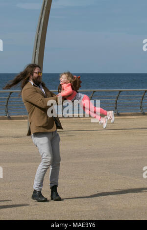 Père & fille sur une journée à Blackpool, Lancashire. Météo britannique. 1er avril 2018. Calme, froide journée ensoleillée sur la côte les vacanciers arrivent à la côte dans l'espoir d'un printemps chaud. Les conditions devraient s'aggraver en début d'après-midi avec la pluie et hailsshowers prévision. Credit : MediaWorldImages/Alamy Live News Banque D'Images