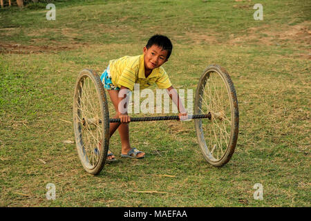 Kid Local jouant avec roues à Vang Vieng, Laos. Vang Vieng est une ville touristiques dans la province de Vientiane. Banque D'Images